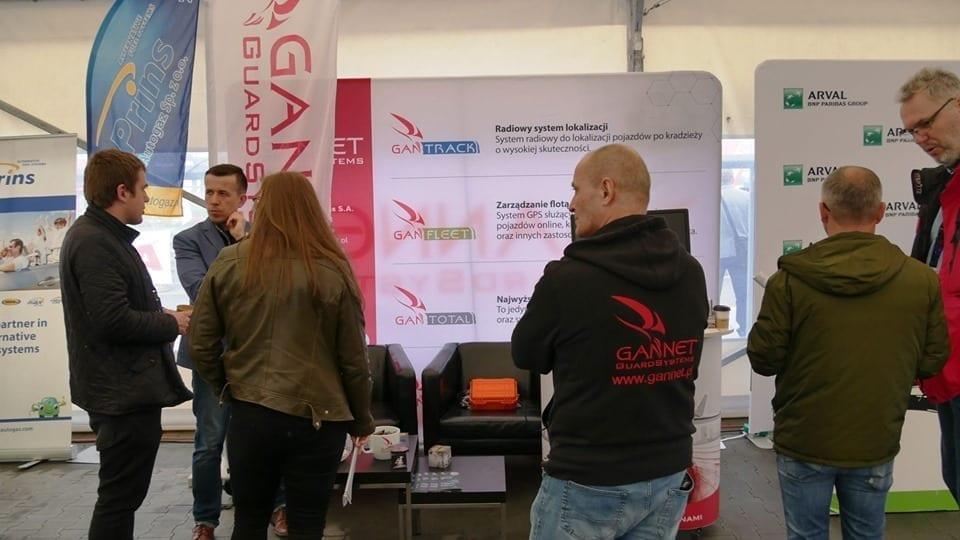 Ludzie rozmawiają przy stoisku wystawowym.