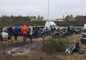 Grupa ludzi wokół quadów na zewnątrz.