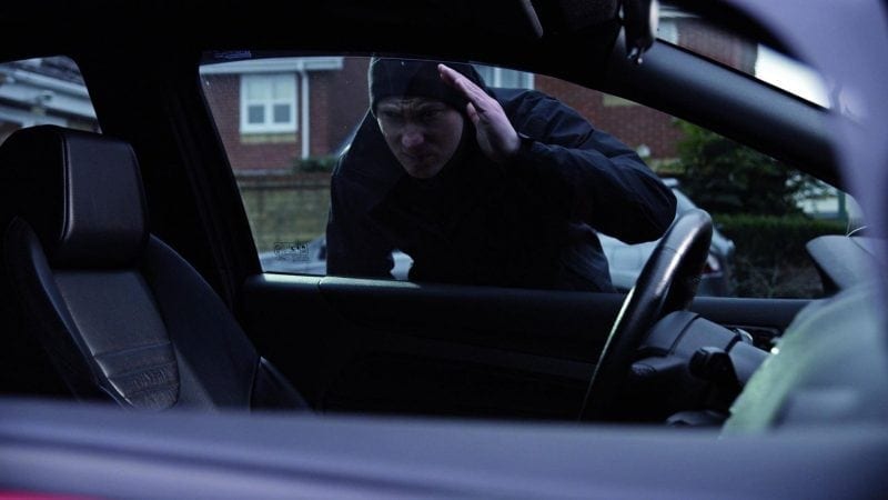 Mężczyzna próbuje włamać się do samochodu.