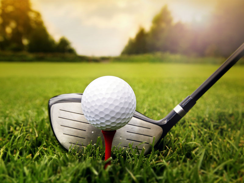 Piłka golfowa na tee z kijem.